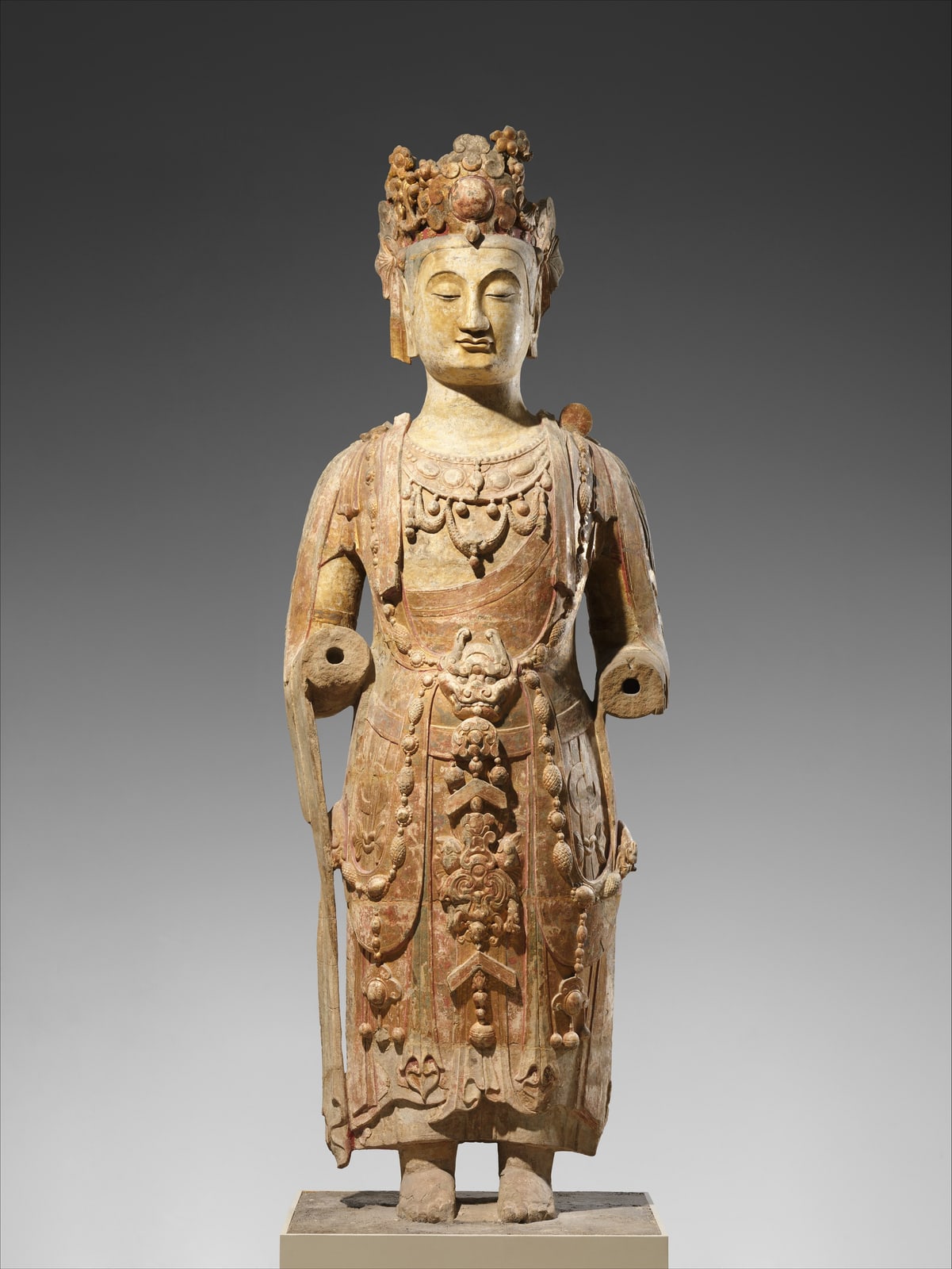 A tall Chinese sandstone bodhisattva wearing flowing garments and elaborate jewelry